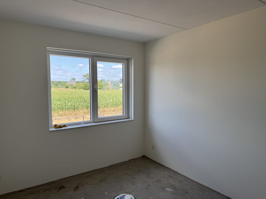 Lege kamer in een nieuwbouwwoning met lichte wanden en een raam, klaar voor de inmeting